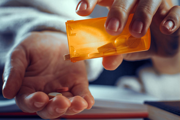 A person holding a prescription pill bottle, indicating medication.